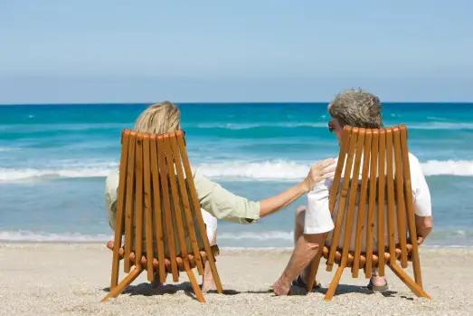 A serene tropical beach with palm trees, clear turquoise waters, and elderly couples strolling.