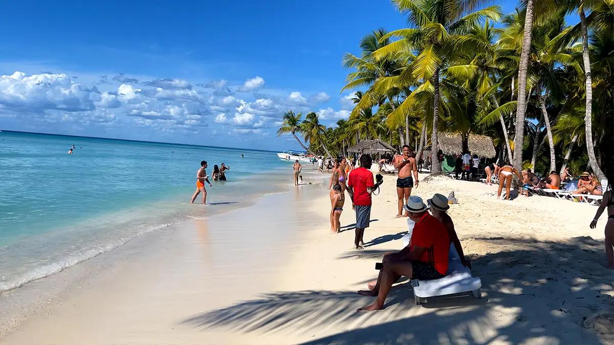 Retirees stroll and sip coffee on Punta Cana's golden beaches, vibrant cottages in the background.