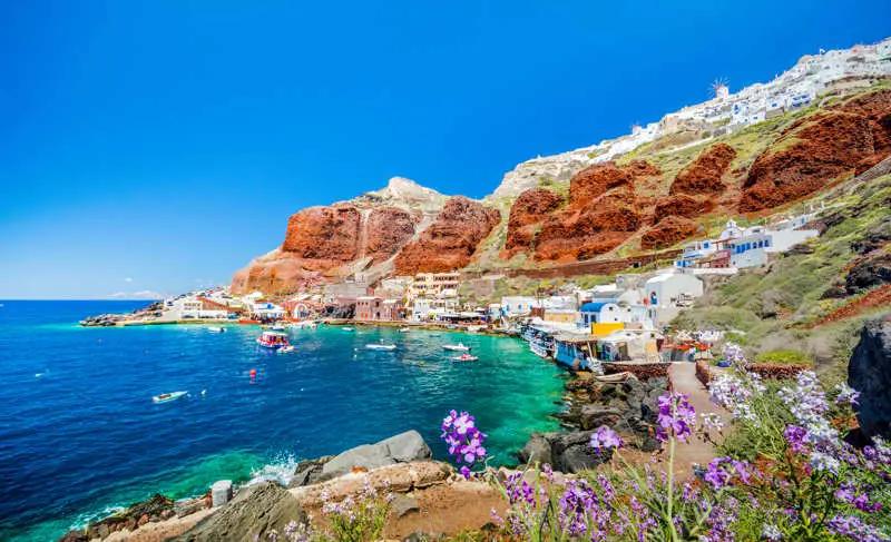 A retired couple enjoys wine and a sunset meal in a picturesque Greek village.