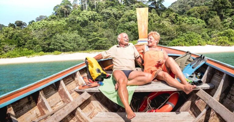 Retired couple under bamboo gazebo by beach, enjoying coconuts with tropical scenery in the Philippines.