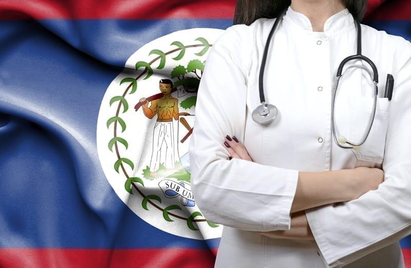 A retired couple in a modern Belizean clinic, greeted by compassionate healthcare staff, with coastal views.