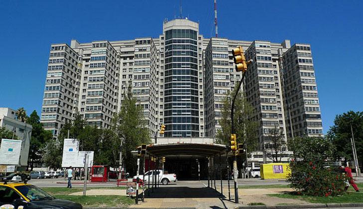 A modern healthcare facility in Uruguay, a happy retired couple greeted by medical staff.